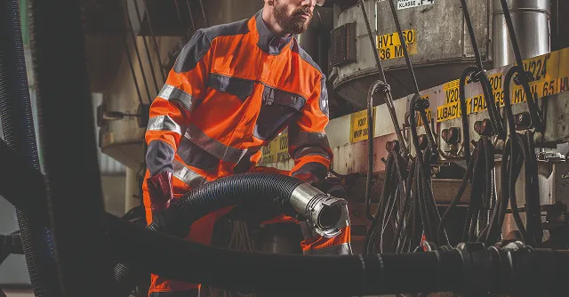 Une personne en tenue de protection manipulant un tuyau 