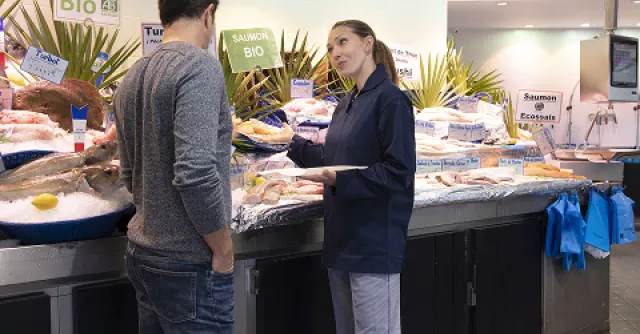 Un client parlant à la personne en charge du rayon poisson