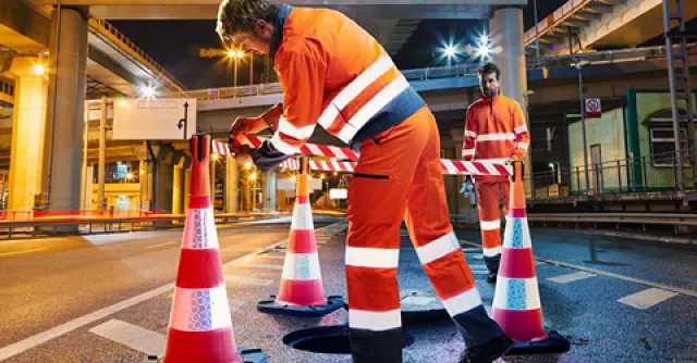 Deux personne portant des EPI orange avec des bandes refléchissantes