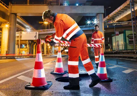 Deux personne portant des EPI orange avec des bandes refléchissantes