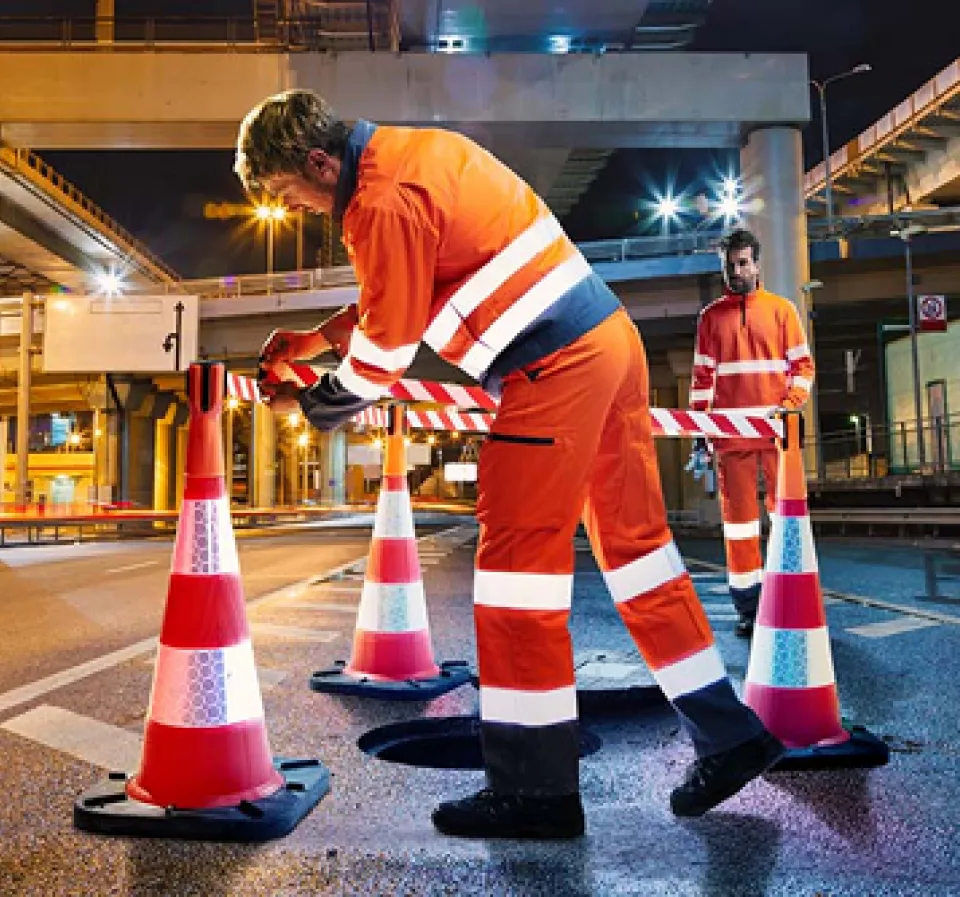 Deux personne portant des EPI orange avec des bandes refléchissantes