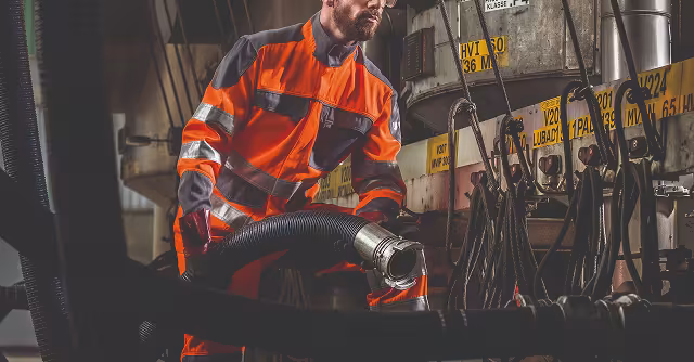 Une personne en tenue de protection manipulant un tuyau 